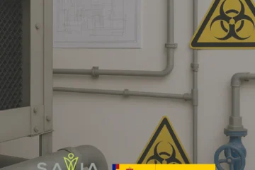 Instalación industrial con tuberías, válvulas y señal de riesgo biológico, representando entornos de aplicación del certificado de profesionalidad de legionella homologado impartido por Savia Formación, con respaldo del Gobierno de España.